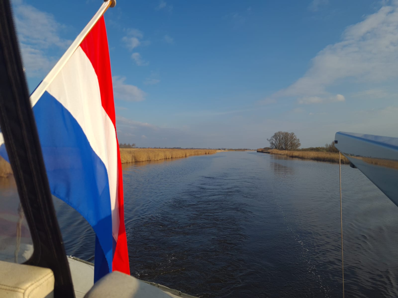 Foto van water met vlag en een prachtige vaart met rietkraag